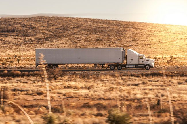 A fleet semi truck on the road during sunset.