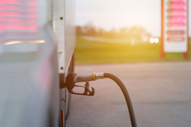 View of a gas pump fueling a truck at a fueling station.